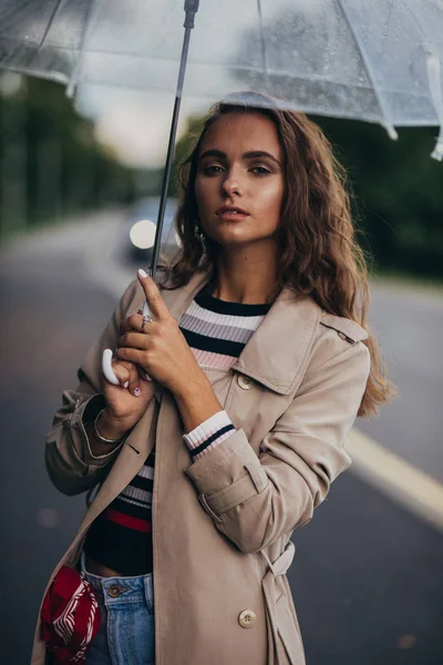 Portraits of a beautiful young woman with umbrella under the rain at the autumn outdoors