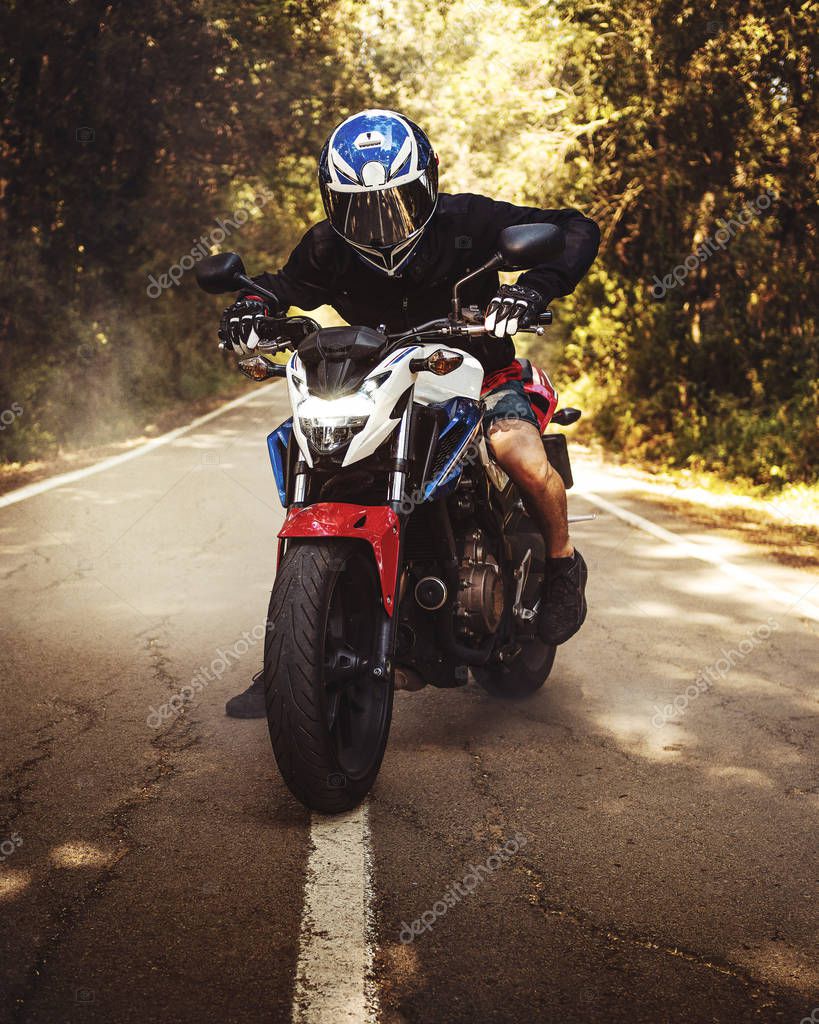 Photoshoot of a guy riding his motorbike with smoke behind it. Agressive photo that shows the power of the bikes and the location is in the forest.