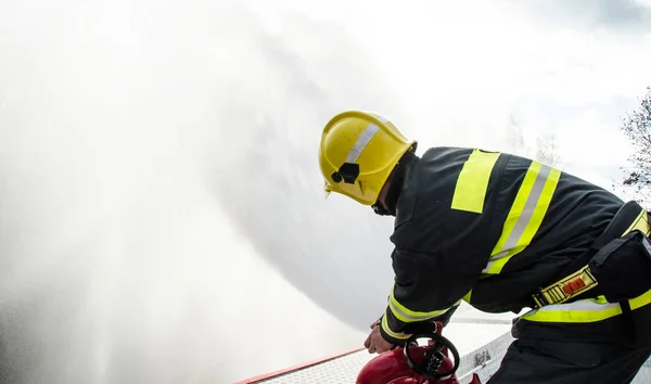 Firefighters with a hose in action — Stock Photo, Image