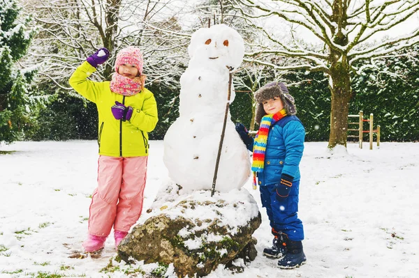 Sıcak kış giyim eşyası birlikte kar parkta oynayan iki sevimli çocuk — Stok fotoğraf