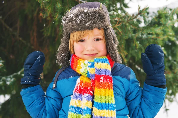 Vinter porträtt av en söt liten pojke under snöfallet, bär varma blå jacka och färgstark halsduk — Stockfoto