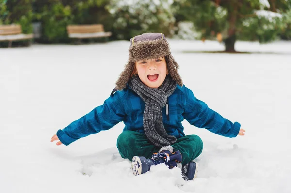 Bonito menino brincando no parque de inverno. Criança se divertindo ao ar livre, correndo na neve, vestindo casaco azul quente, chapéu e cachecol — Fotografia de Stock