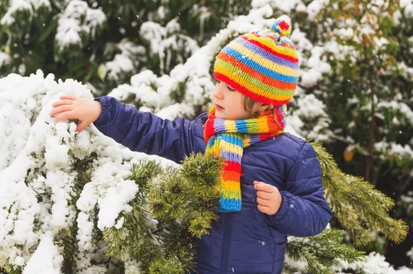 Retrato ao ar livre jovem menino de 4 anos vestindo casaco azul, conjunto colorido de chapéu de malha artesanal e cachecol, desfrutando de tempo de inverno — Fotografia de Stock