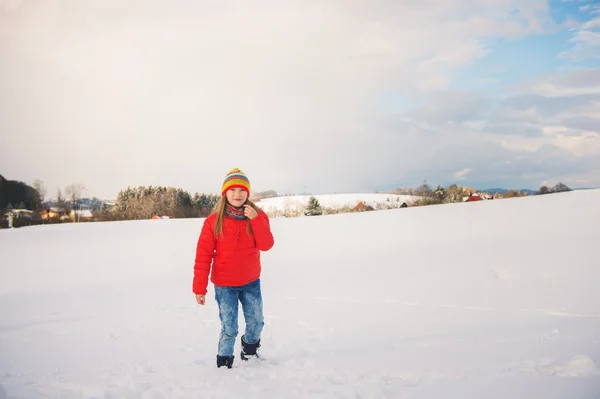 小女孩穿红色上衣和色彩鲜艳的帽子，玩雪在冬天的时候 — 图库照片