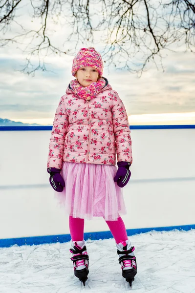 Söpö pieni tyttö luistelu jäähalli yllään vaaleanpunainen vaatteita — kuvapankkivalokuva