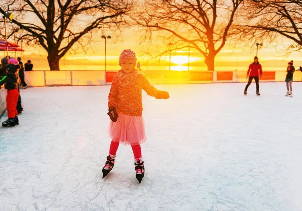 Söt liten flicka på skridskobana i solnedgången ljus — Stockfoto