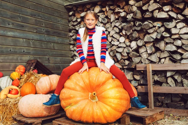 Adorable little girl of 8-9 year old choosing halloween pumpkin on farm market — Stock Photo, Image