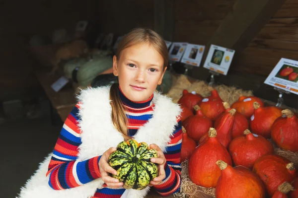 Aranyos kislány, 8-9 év régi kiválasztása halloween tök farm piacon — Stock Fotó
