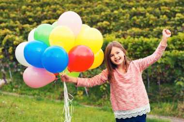 Mutlu küçük 8-9 yıl yaşlı kız renkli balonlar ile