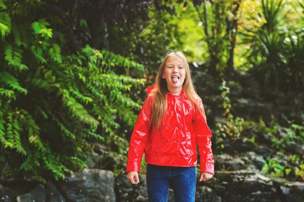Urocza dziewczynka połowu deszcz spadnie z jej język, noszenie czerwony deszcz marynarka — Zdjęcie stockowe