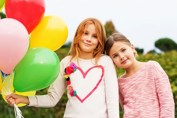 Outdoor Portret van 2 schattige kleine meisjes met kleurrijke ballonnen — Stockfoto