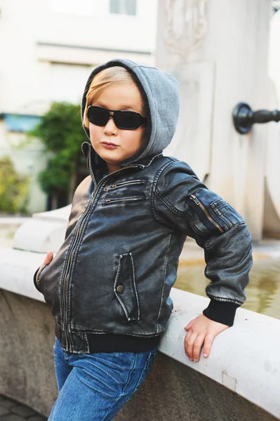 Außenporträt eines entzückenden kleinen blonden Jungen mit schwarzer Lederjacke und Sonnenbrille — Stockfoto