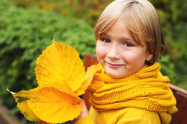 Herfst dicht omhoog portret van schattige kleine jongen met bladeren, gele warme sweater en gebreide sjaal dragen — Stockfoto