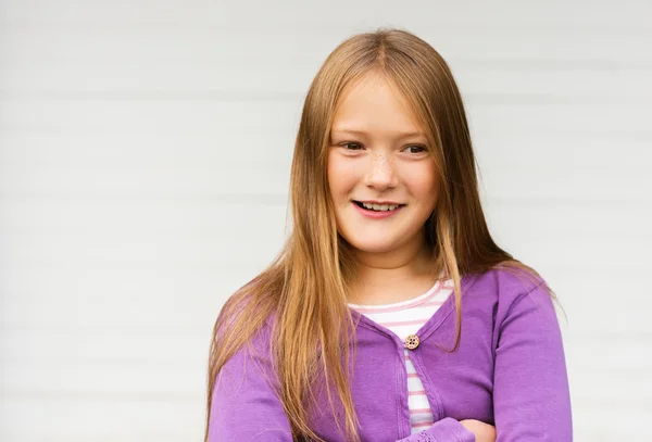 Ritratto all'aperto di carina bambina di 8-9 anni con i capelli lunghi, indossando giacca viola, in piedi su sfondo bianco — Foto Stock