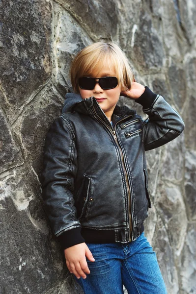 Πορτραίτου του αξιολάτρευτο μικρό ξανθό αγόρι φορώντας μαύρο δερμάτινο μπουφάν και γυαλιά ηλίου — Φωτογραφία Αρχείου