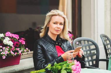 Açık smartphone kullanarak kafe, dinlenme pembe gül buketi tutan güzel sarışın kadın portresi