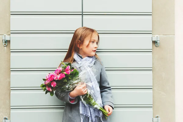 Outdoor portrait of 5-6 year old little girl wearing grey coat and scarf, holding bouquet of pink roses — Stock Photo, Image