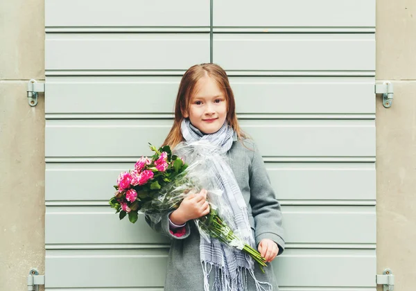 Outdoor portrait of 5-6 year old little girl wearing grey coat and scarf, holding bouquet of pink roses — Stock Photo, Image