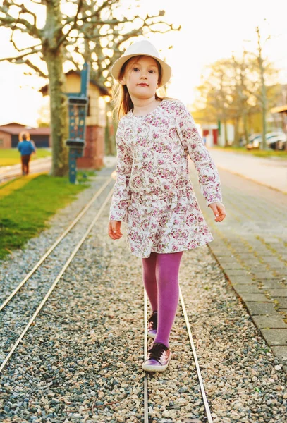 Niña de 5-6 años jugando al aire libre al atardecer, usando sombrero, hermoso vestido, medias y zapatos morados — Foto de Stock
