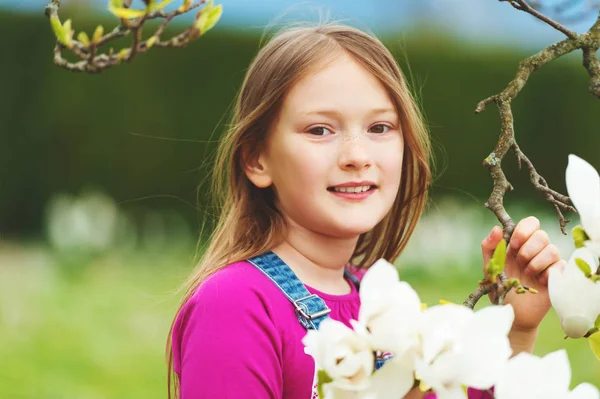 Spring portrait of 7-8 year old pretty little girl with magnolia flowers — Stock Photo, Image