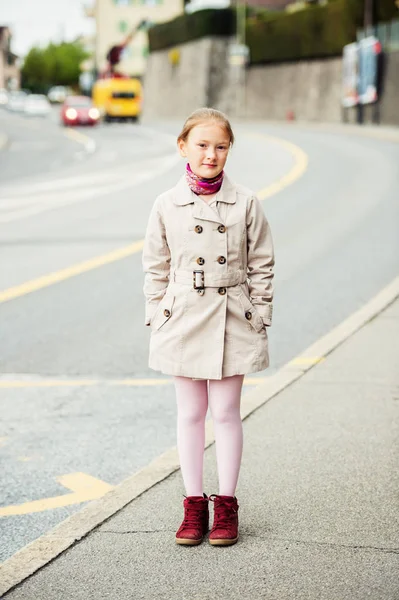年轻的孩子女孩穿米色风衣和红色靴子的室外肖像 — 图库照片
