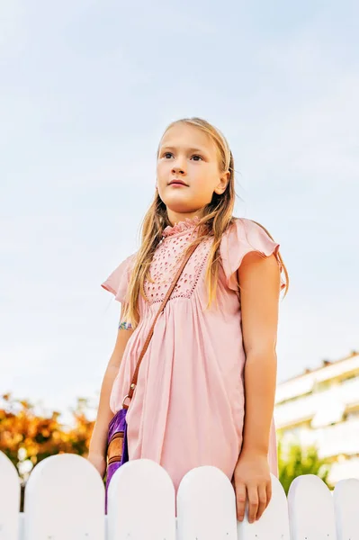 Outdoor portrait of cute 8-9 year old girl wearing pink dress — Stock Photo, Image