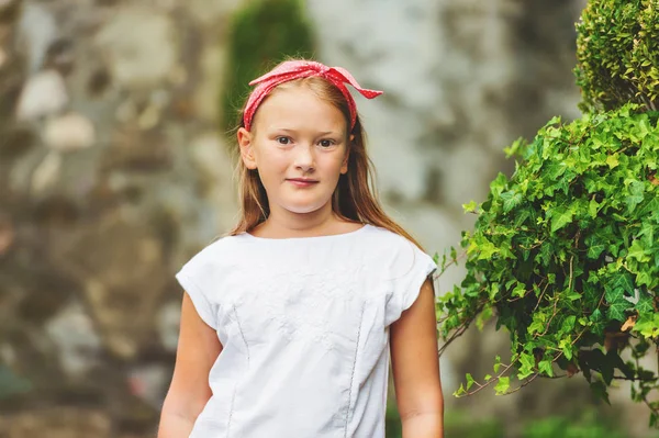 Outdoor portrait of cute 8-9 year old girl wearing red headband — Stock Photo, Image