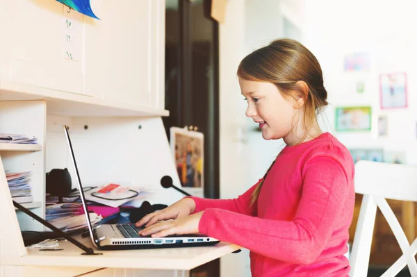 Маленькая девочка делает домашнее задание с ноутбуком — стоковое фото