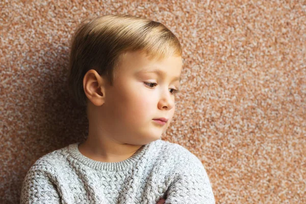 Handsome little 5-6 year old boy posing against brown background, wearing grey pullover — Stock Photo, Image