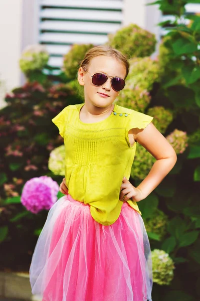 Retrato al aire libre de una linda niña con camisa verde, falda de tutú rosa, gafas de sol — Foto de Stock