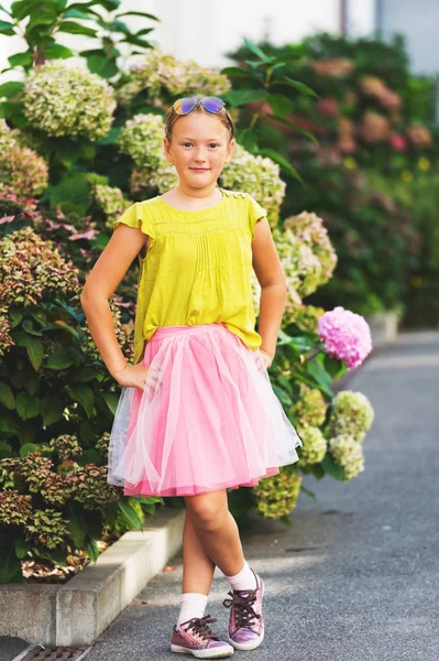 Retrato al aire libre de una linda niña con camisa verde, falda de tutú rosa, gafas de sol — Foto de Stock