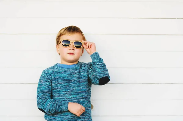 Retrato de moda del adorable niño usando jersey de punto azul y gafas de sol — Foto de Stock