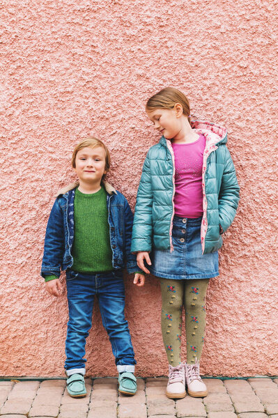 Fashion portrait of adorable kids wearing warm jackets and shoes