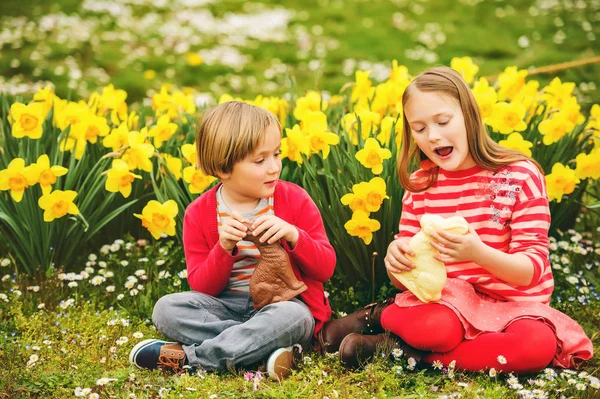Schattige kleine kinderen, grote zus en kleine broer, met chocolade Pasen konijntjes traditionele feest vieren. Vakantie met het gezin, lente, zorgeloze kindertijd concept. — Stockfoto