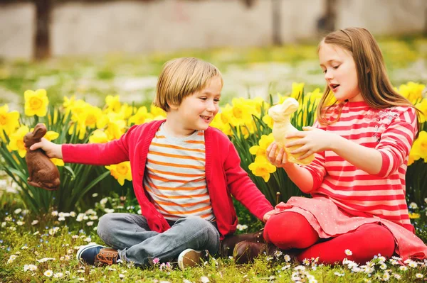 Niedliche kleine Kinder, große Schwester und kleiner Bruder, mit Schokoladen-Osterhasen, die traditionelles Fest feiern. Familie, Urlaub, Frühling, unbeschwerte Kindheit. — Stockfoto