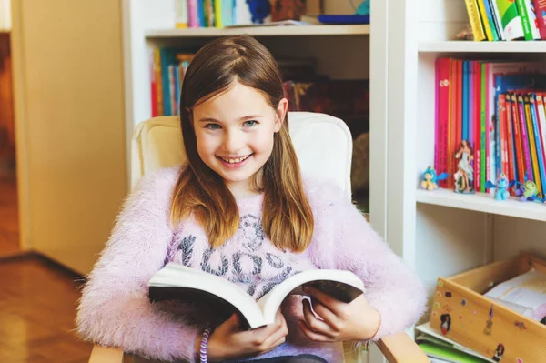 Retrato de criança de 8-9 anos de idade leitura livro em casa — Fotografia de Stock