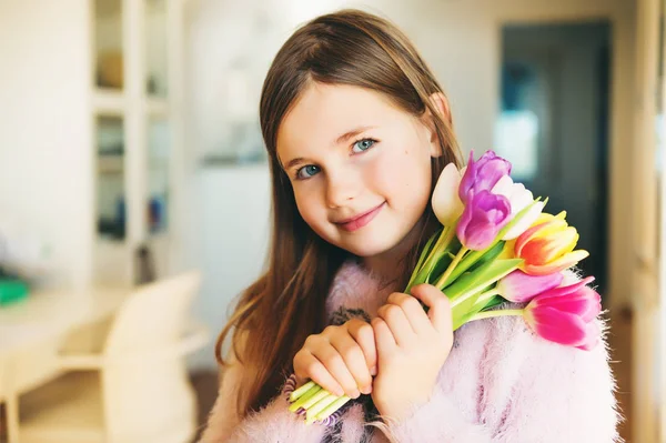 Adorável menina sorridente com olhos azuis segurando pequeno buquê de tulipas frescas brilhantes — Fotografia de Stock