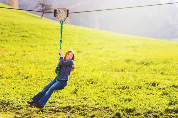 Carina bambina che gioca su un'altalena a catena, si diverte in un parco in una bella giornata di sole in primavera — Foto Stock