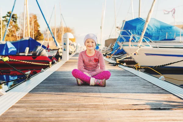 Kleines Mädchen ruht sich im Frühjahr auf Seebrücke aus — Stockfoto