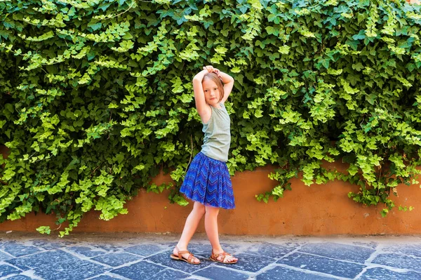 Zomer mode voor kids, outdoor portret van een schattig klein meisje dragen blauwe rok, groene top en bruine lederen schoenen — Stockfoto