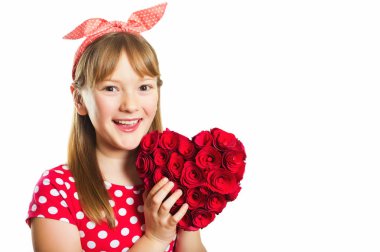 Genç küçük 9-10 yıl yaşlı kız, kırmızı puantiyeli elbise ve beyaz arka plan üzerinde izole kafa bandı, stüdyo çekim büyük dekorasyon kalp, Saint Valentine kavramı holding biçemi pin