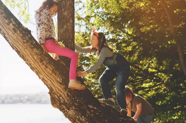Gruppo di giovani ragazzi felici che giocano fuori in una bella giornata estiva, rivendicando un albero — Foto Stock