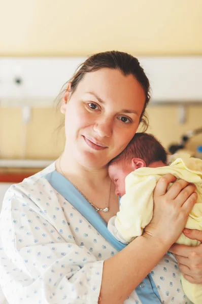 Yeni doğan bebeğin doğumdan sonra hastanede ile mutlu ve yorgun genç anne 