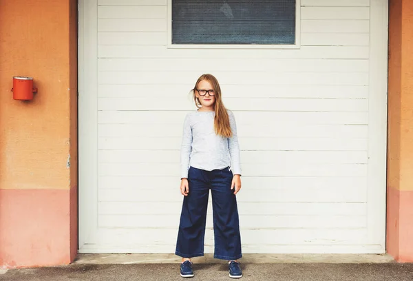 Buiten grappige portret van een schattige kleine 9-10 jaar oud meisje dragen blauwe bovenkant, denim culottes en brillen — Stockfoto