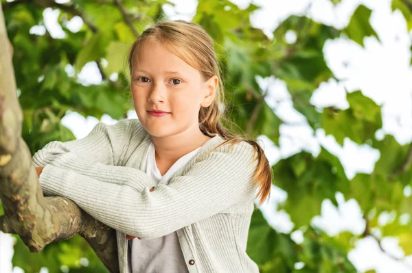 Buiten close-up portret van schattige kleine 8-9 jaar oud meisje leunend op een boom — Stockfoto