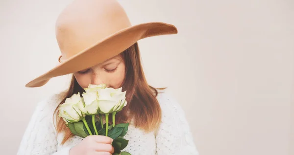 Menina bonita usando um chapéu, segurando buquê de rosas brancas, de pé contra fundo bege — Fotografia de Stock