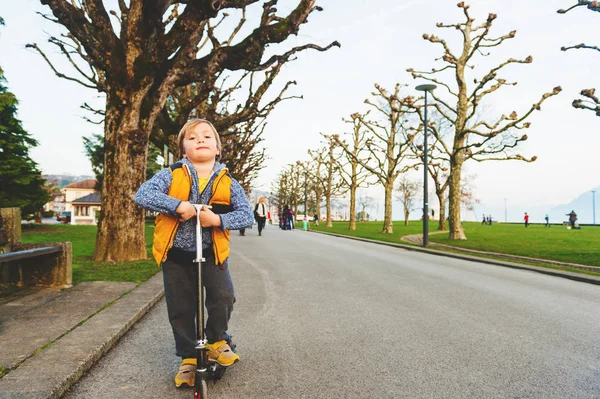 Little boy riding scooter in the park in early spring — Stock Photo, Image