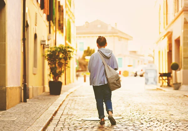 Девочка с рюкзаком идет по булыжной дороге в старой швейцарской деревне — стоковое фото