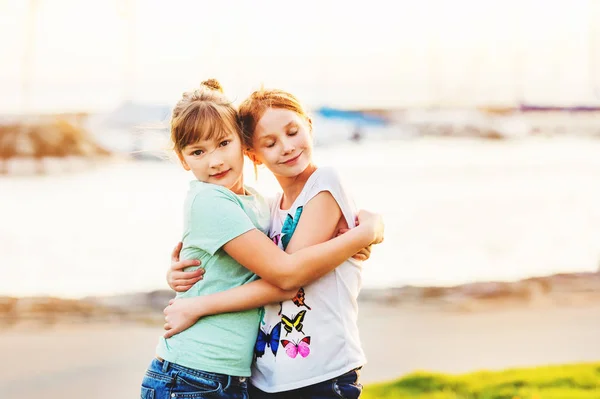 Zwei 9-10 jährige Mädchen spielen zusammen draußen, umarmen sich, goldene Stunde — Stockfoto