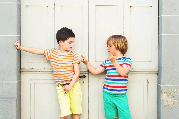 Gruppo di due simpatici ragazzini che giocano insieme all'aperto, indossando magliette e pantaloncini colorati, moda estiva per bambini . — Foto Stock